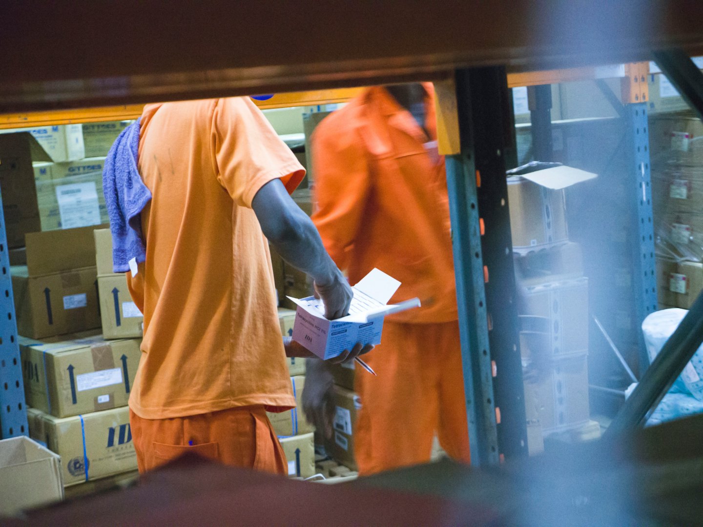 Workers in orange uniforms sort packages in a busy warehouse.