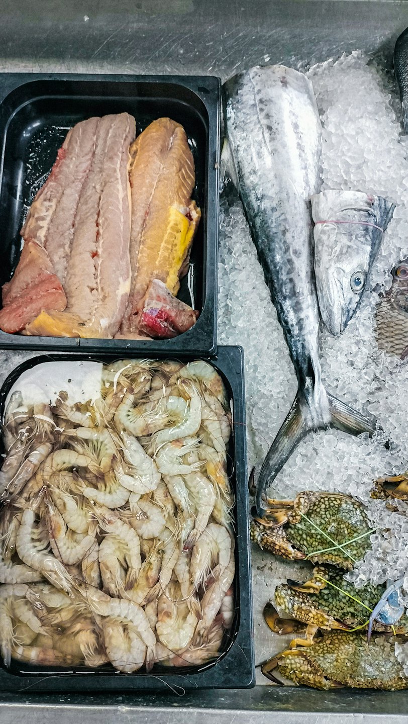 Fresh fish and shrimp displayed on a bed of ice.