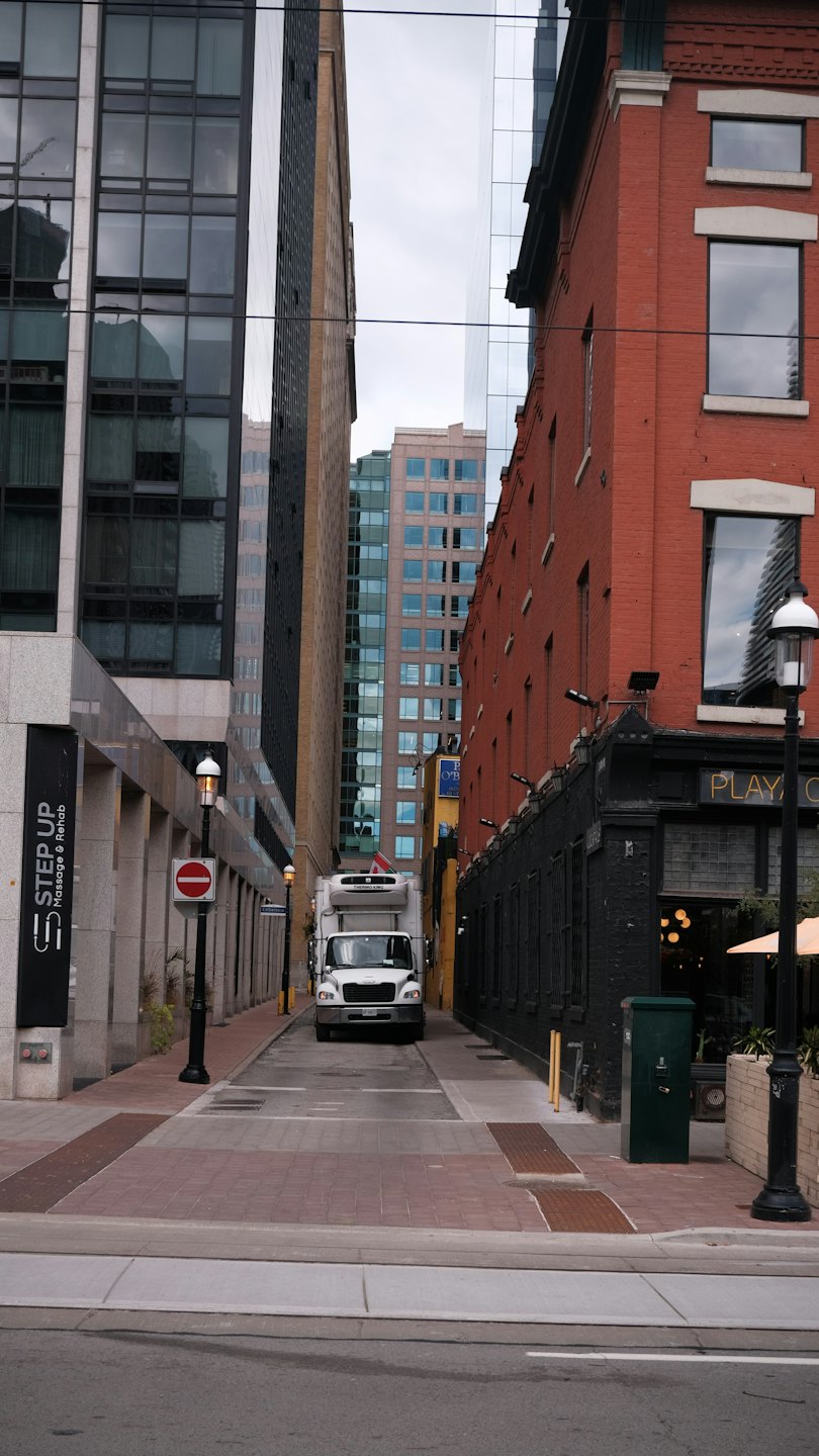 White delivery truck parked in an urban city alleyway.
